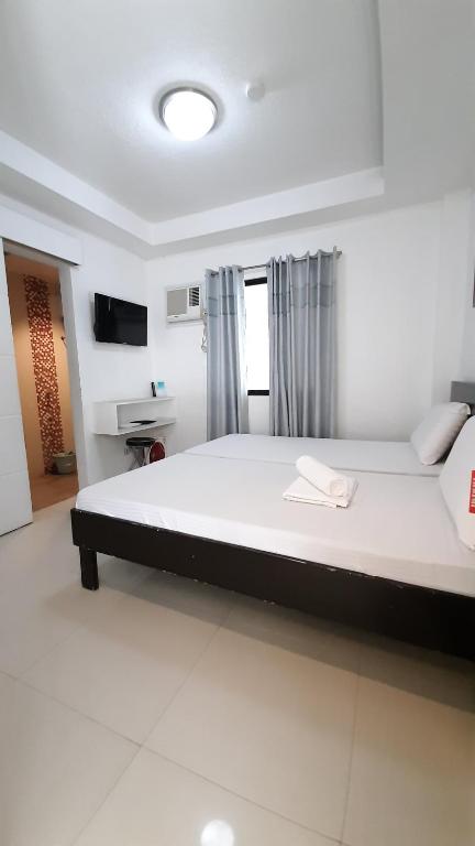 a large white bed in a room with a television at Livewire Planet Suites in General Santos