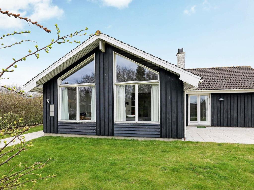 Slettestrandにある10 person holiday home in Fjerritslevの大きな窓と緑の芝生がある黒い家