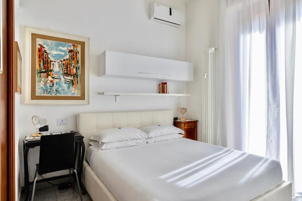 um quarto branco com uma cama, uma secretária e uma janela em Aiello Suites Milan em Milão