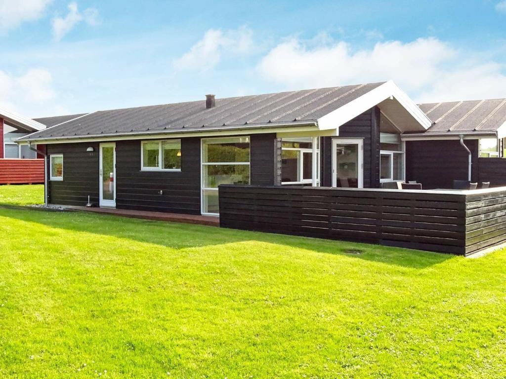 a black house with a green lawn in front of it at 6 person holiday home in Tranek r in Tranekær