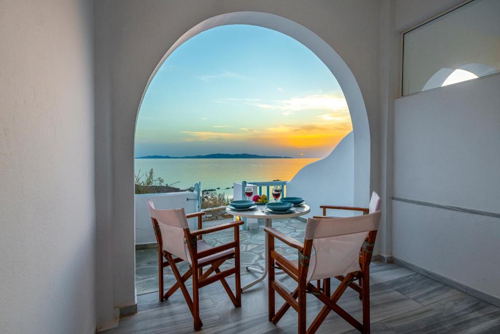 Aegean Dream Apartments في تينوس تاون: غرفة طعام مع ممر وطاولة وكراسي