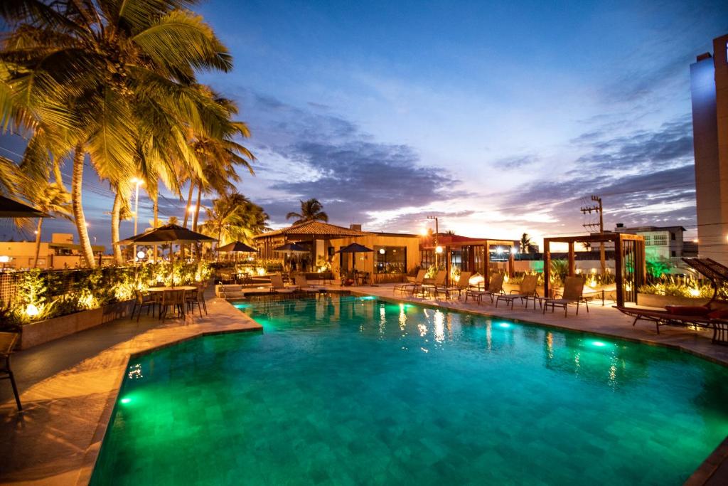 una piscina con sillas y palmeras por la noche en Celi Hotel Aracaju, en Aracaju