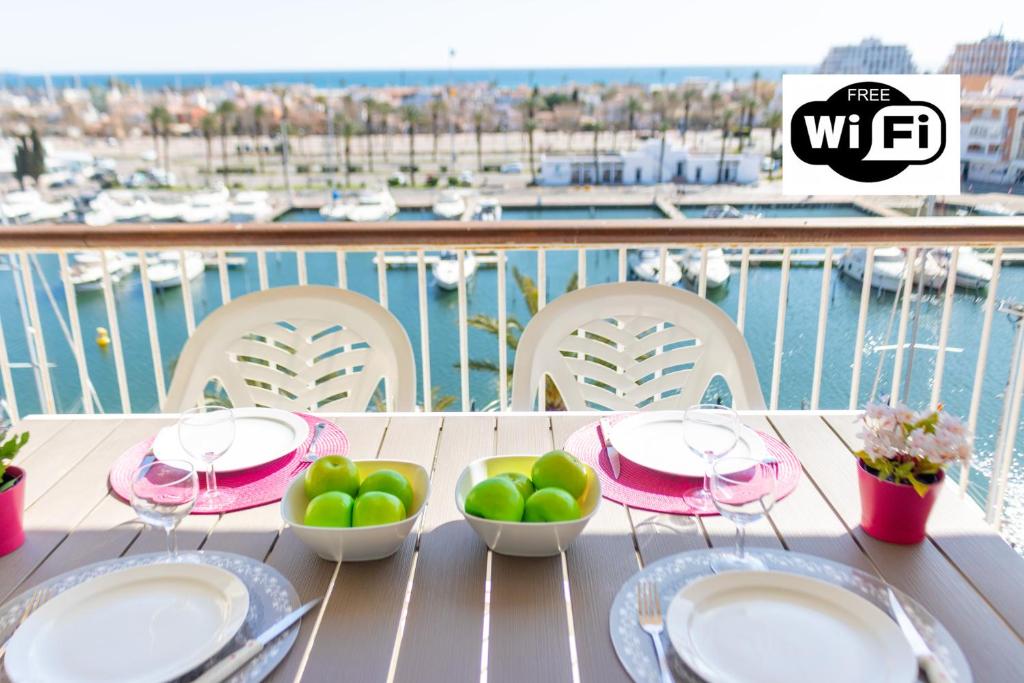 une table avec des assiettes et des bols de fruits sur un balcon dans l'établissement Apart-rent Apartamento Port Grec 0161, à Empuriabrava