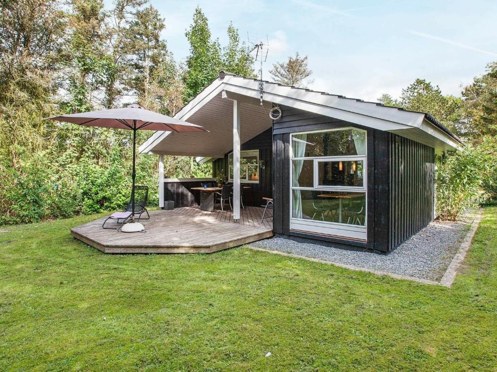 um pequeno barracão preto com um guarda-chuva no relvado em Five-Bedroom Holiday home in Juelsminde 1 em Slagelse