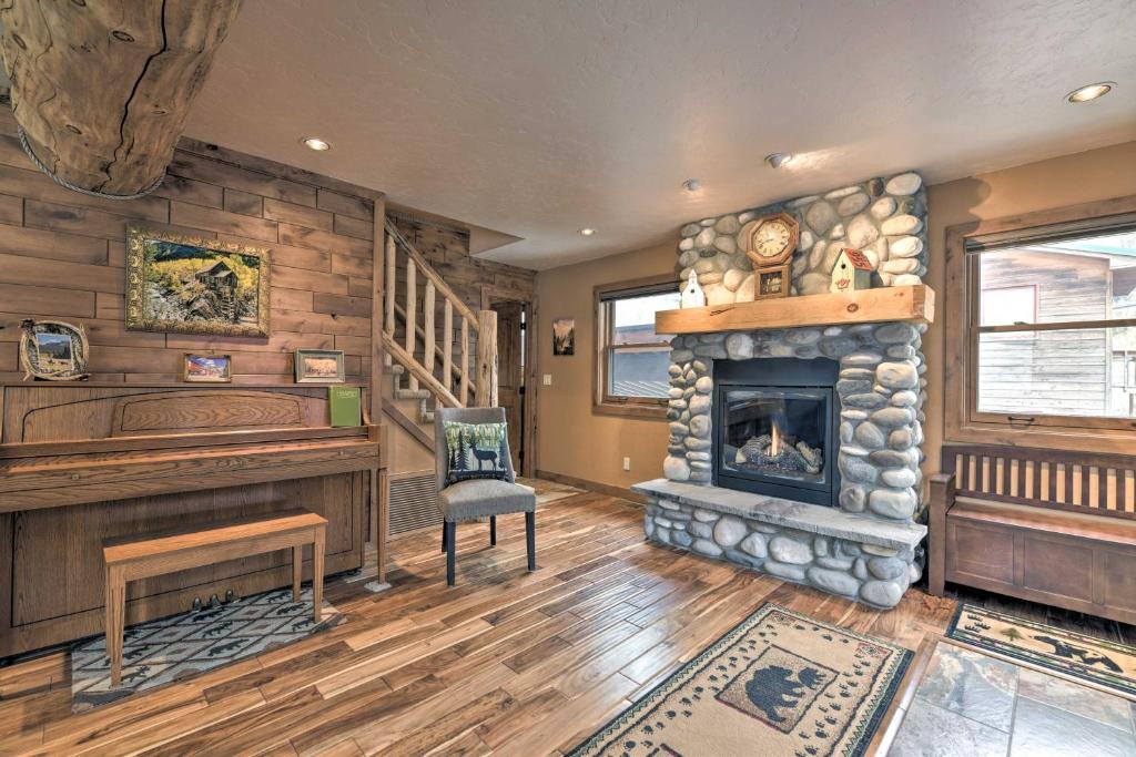 a living room with a stone fireplace and a desk at Updated Mtn Home with Deck on Uncompahgre River in Ouray