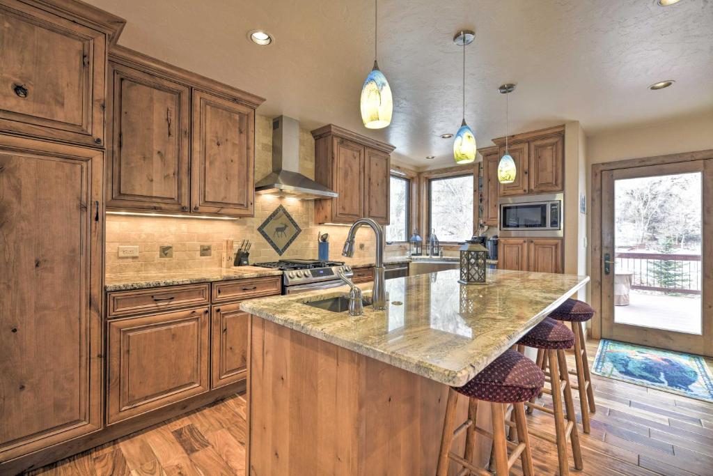 a kitchen with wooden cabinets and a large island with bar stools at Updated Mtn Home with Deck on Uncompahgre River in Ouray
