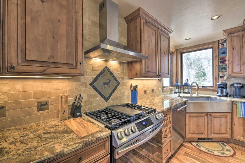 a kitchen with wooden cabinets and a stove top oven at Updated Mtn Home with Deck on Uncompahgre River in Ouray