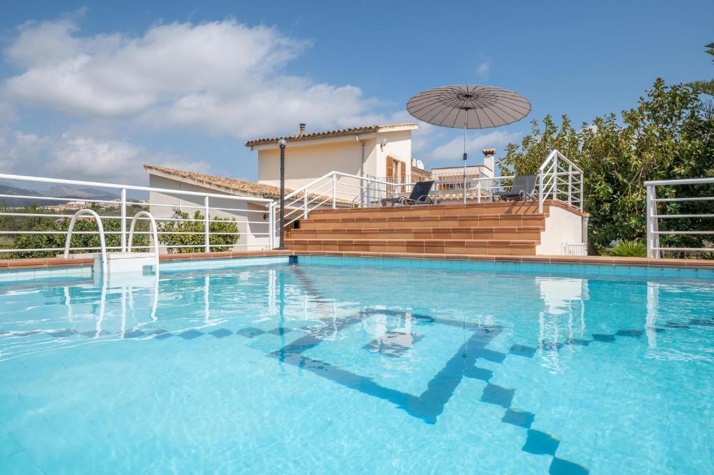 a large swimming pool with chairs and an umbrella at Can Nina in Campanet