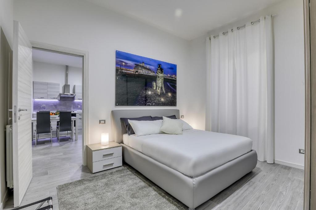 a white bedroom with a bed and a dining room at Tourist Apartment Civitavecchia in Civitavecchia