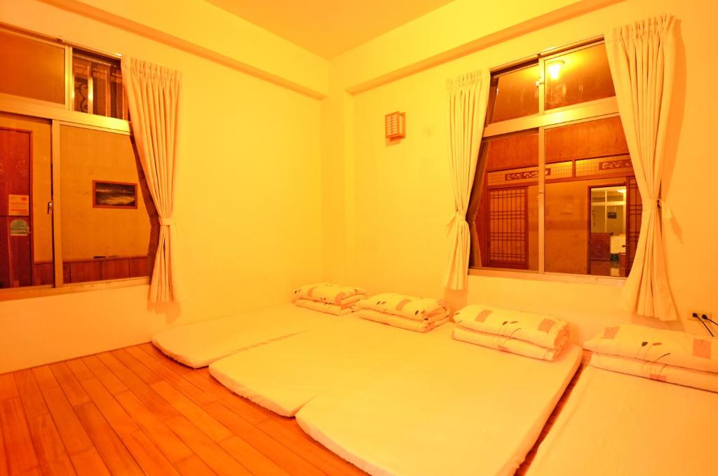 a bedroom with two beds and two windows at Alishan Fenqihu Green Land Homestay in Guanghua
