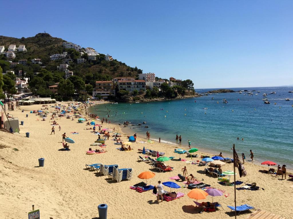 eine Gruppe von Menschen am Strand mit Sonnenschirmen in der Unterkunft Villa Buraux III in Roses