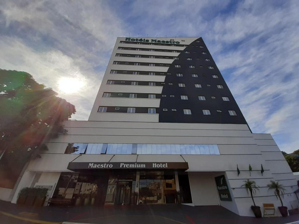 ein hohes Gebäude mit der Sonne im Hintergrund in der Unterkunft Hotel Maestro Premium Cascavel in Cascavel