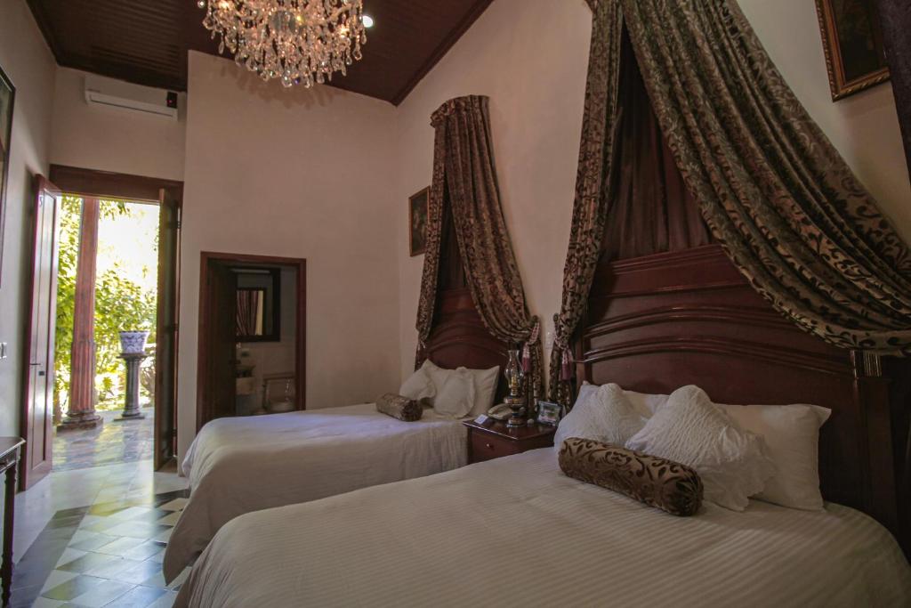 1 dormitorio con 2 camas y lámpara de araña en La Casa del Marqués, en Comitán de Domínguez