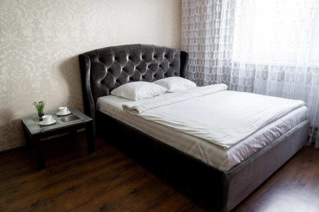 カリーニングラードにあるApartment Prestigeのベッド(黒いヘッドボード、サイドテーブル付)