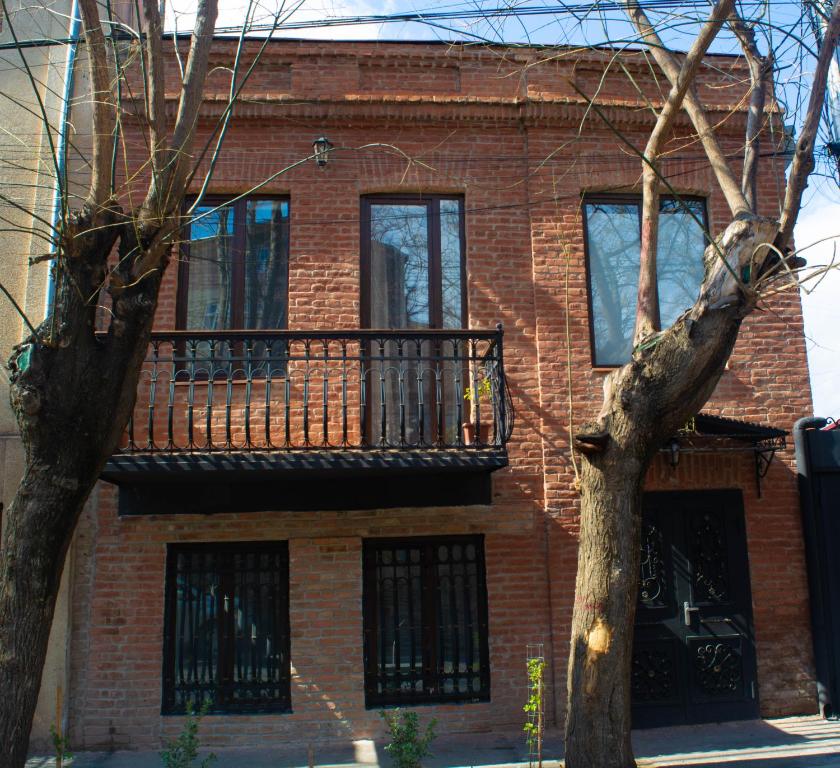 - un bâtiment en briques avec un balcon et un arbre dans l'établissement Sunflower Hotel, à Tbilissi