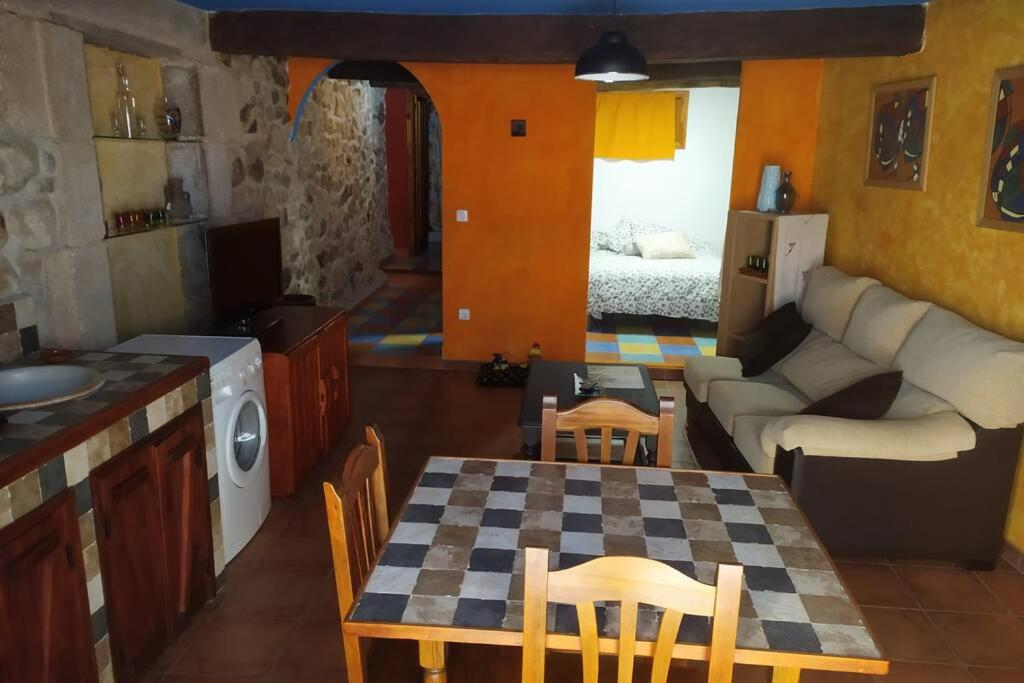 a kitchen and living room with a table and a couch at LOS ORIZOS Sierra de Gata Extremadura TR-CC-00392 in Villamiel