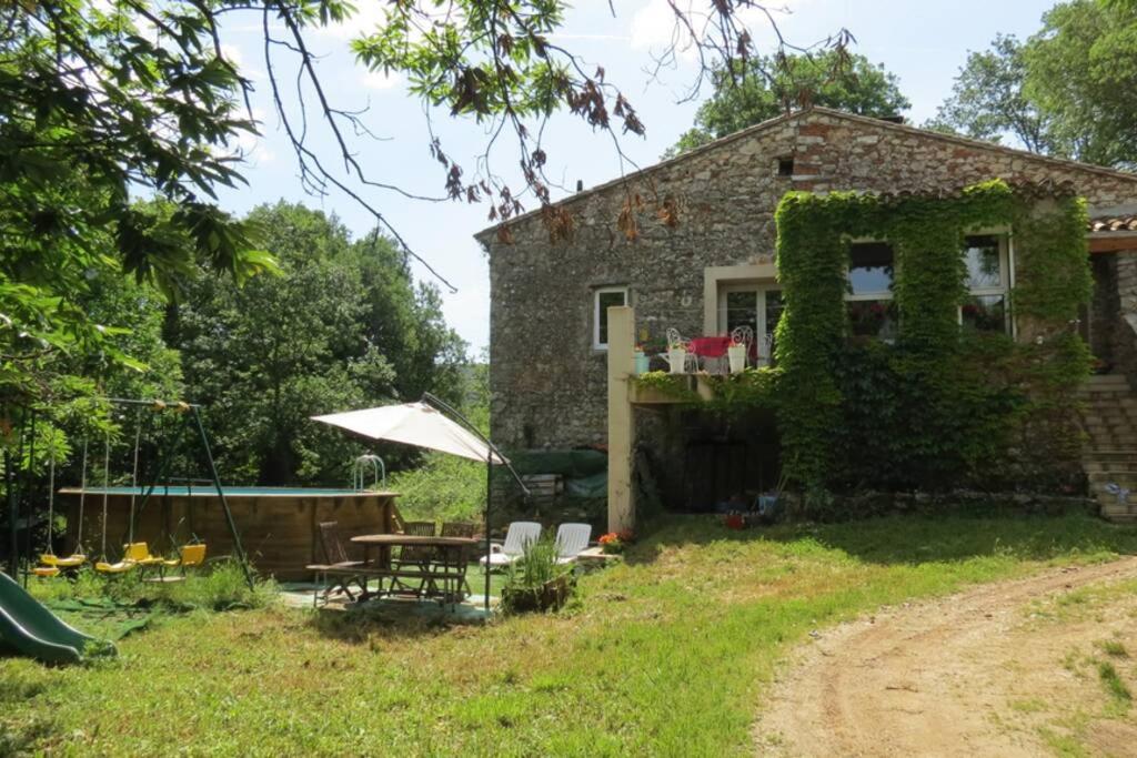 une maison en briques avec une table et des chaises dans la cour dans l'établissement Les châtaigniers du Thaurac, à Saint-Bauzille-de-Putois
