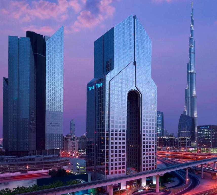 wysoki szklany budynek w mieście w nocy w obiekcie Dusit Thani Dubai w Dubaju