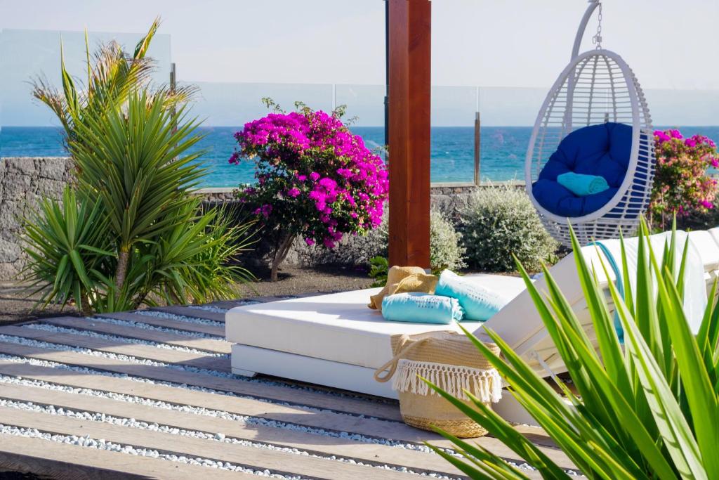a patio with a couch and a swing and the ocean at Hotel Lava Beach in Puerto del Carmen