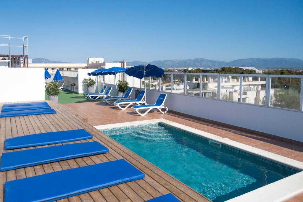 a blue and white swimming pool with blue chairs and umbrellas at Hotel Marbel in Can Pastilla