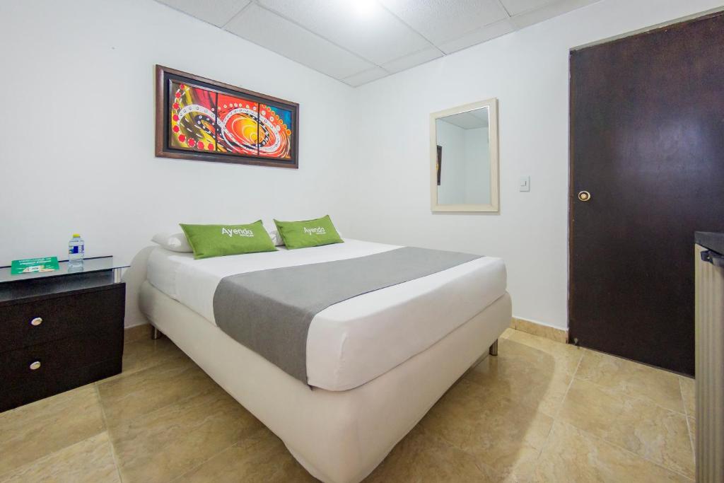 a bedroom with a large white bed with green pillows at Hotel Ayenda Puerto Vigia 1807 in Cartagena de Indias