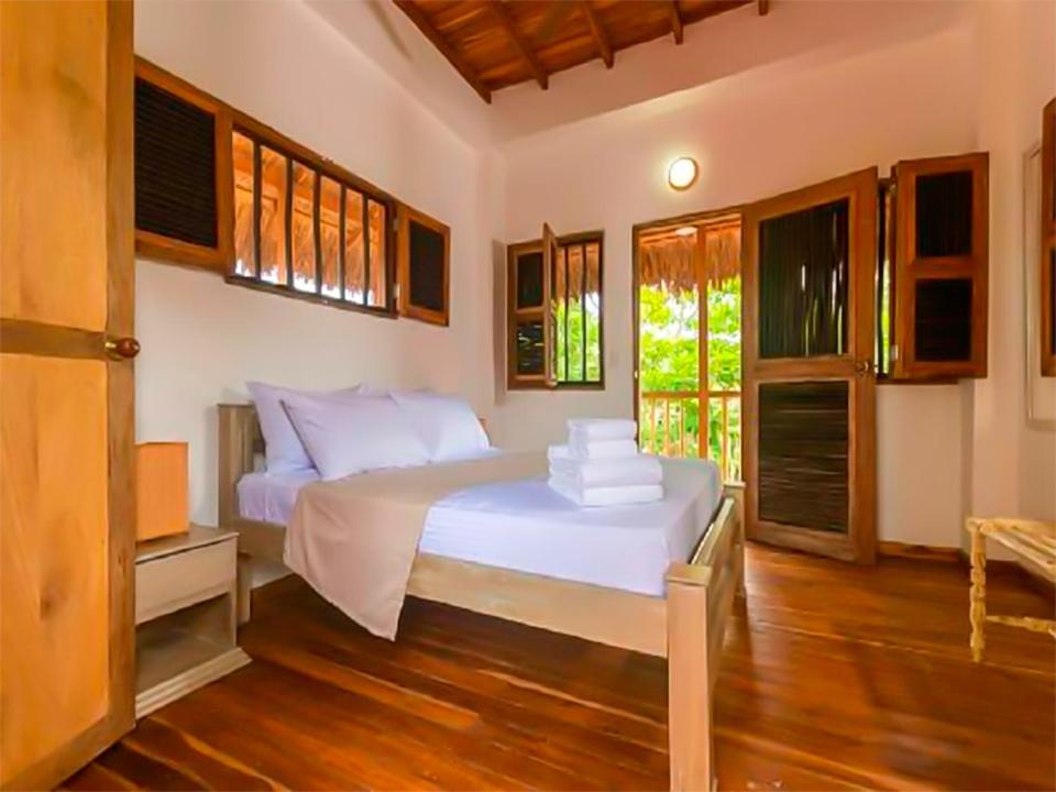 a bedroom with a large white bed with wooden floors at Samadhi Ecohotel by Rotamundos in Puerto Escondido
