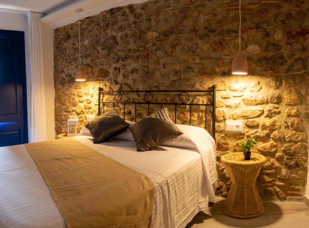 a bedroom with a bed and a stone wall at Knysna Boutique Rooms in Peniscola