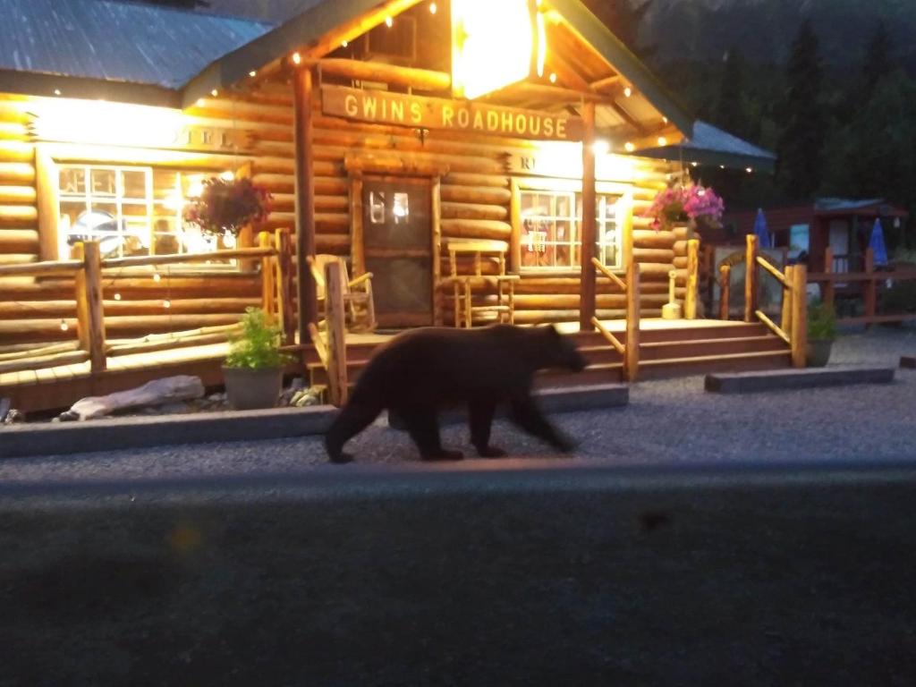 a bear walking in front of a log cabin at Gwin's Lodge & Roadhouse in Cooper Landing