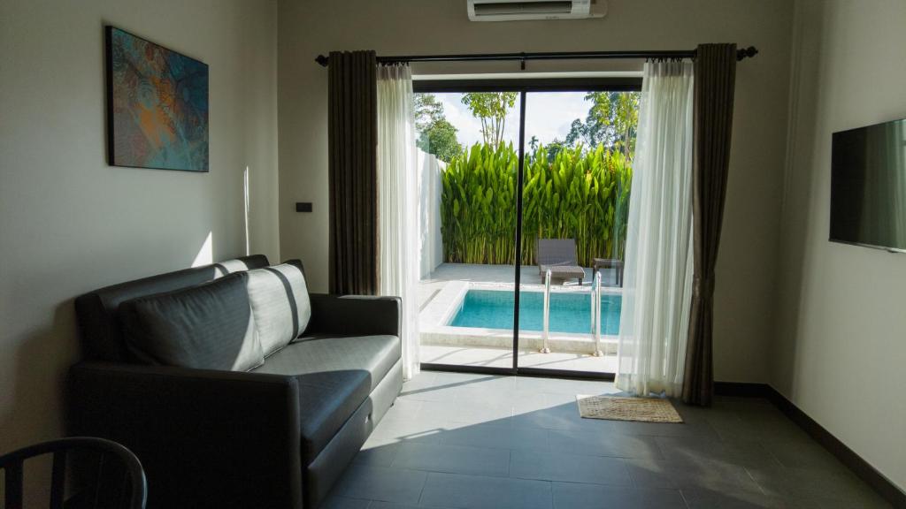sala de estar con sofá y puerta corredera de cristal en Toledo Pool Villa, en Nakhon Si Thammarat