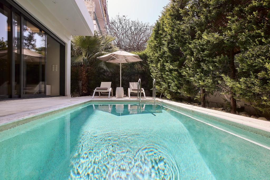 a swimming pool with two chairs and an umbrella at Elaia Luxury Condo Glyfada in Athens