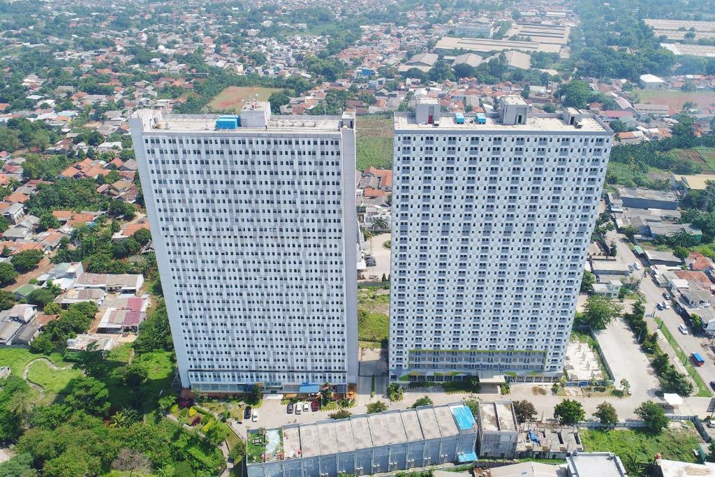 dos altos edificios blancos parados uno al lado del otro en Apartemen Gunung Putri Square by Sirooms, en Bogor