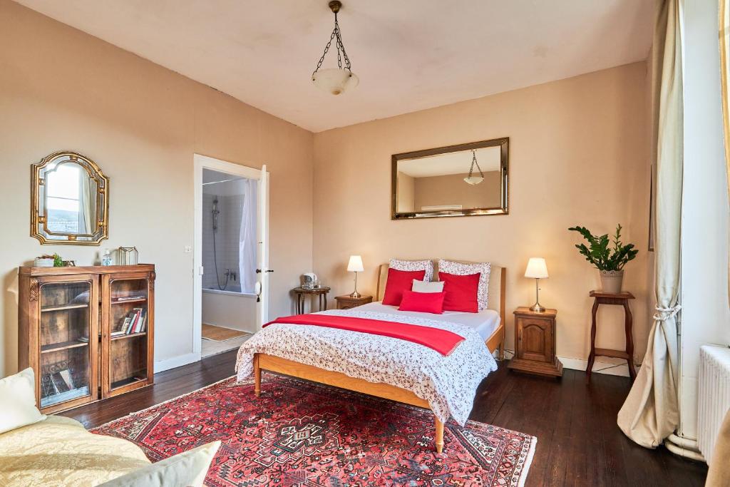 ein Schlafzimmer mit einem Bett mit roten Kissen darauf in der Unterkunft Le Manoir des Doyens in Bayeux