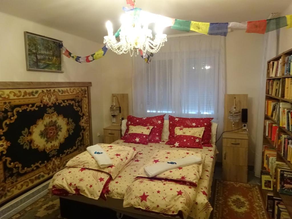 Un dormitorio con una cama con almohadas rojas y una lámpara de araña. en Deluxe szoba, en Eger