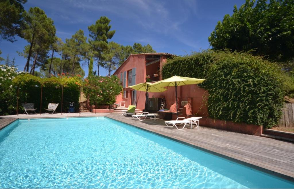 een zwembad met een parasol en stoelen en een huis bij Les flamants roses in Roussillon