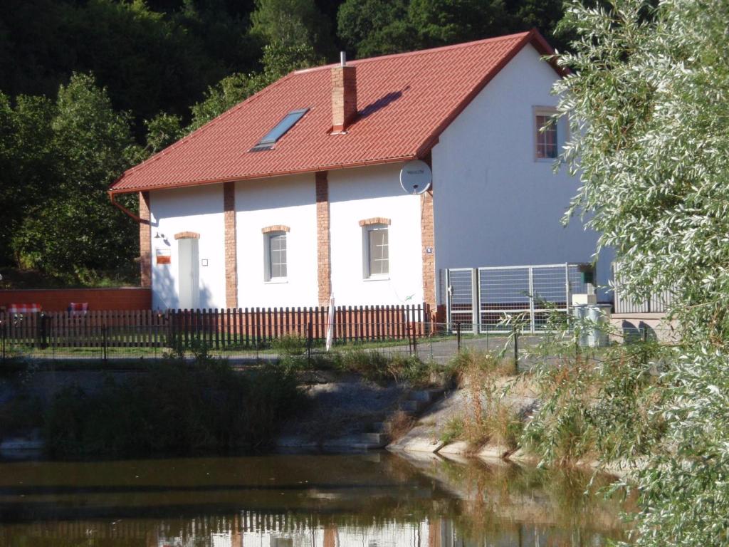 a white house with a red roof next to a river at Apartman75 in Tišnov