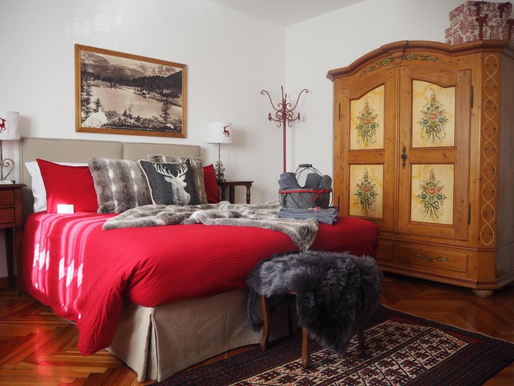 Un dormitorio con una cama roja con un perro. en B&B Sotto Al Bosco, en Spiazzo