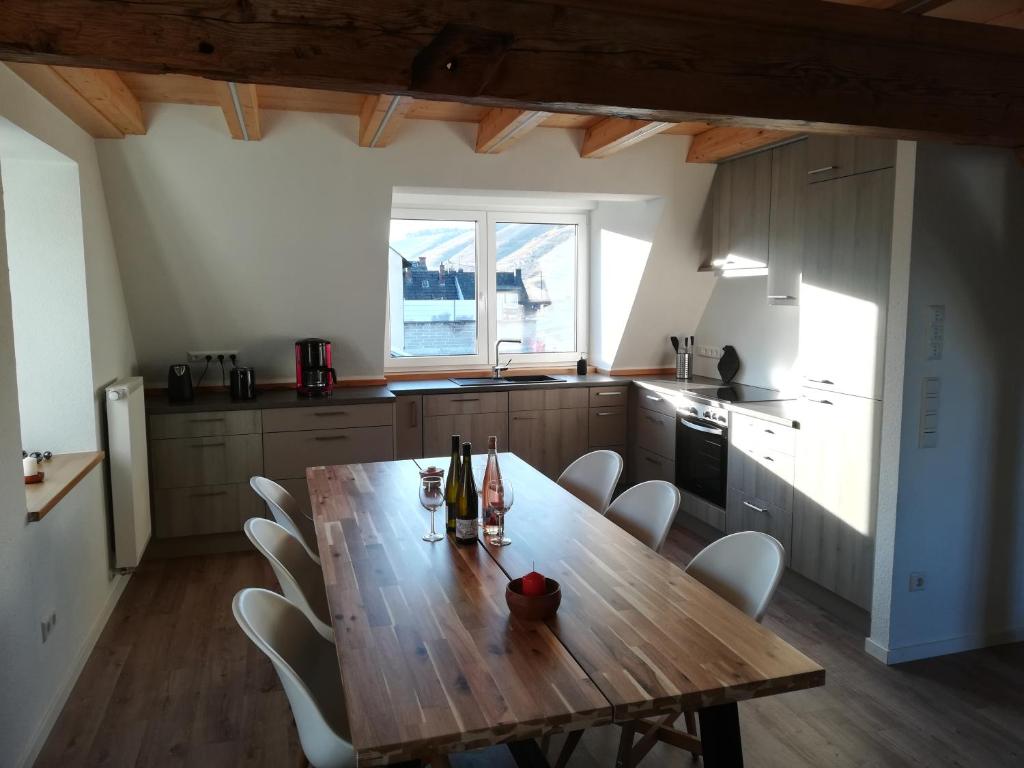 uma cozinha com uma mesa de madeira e cadeiras brancas em Präsenzhof Lay em Lay