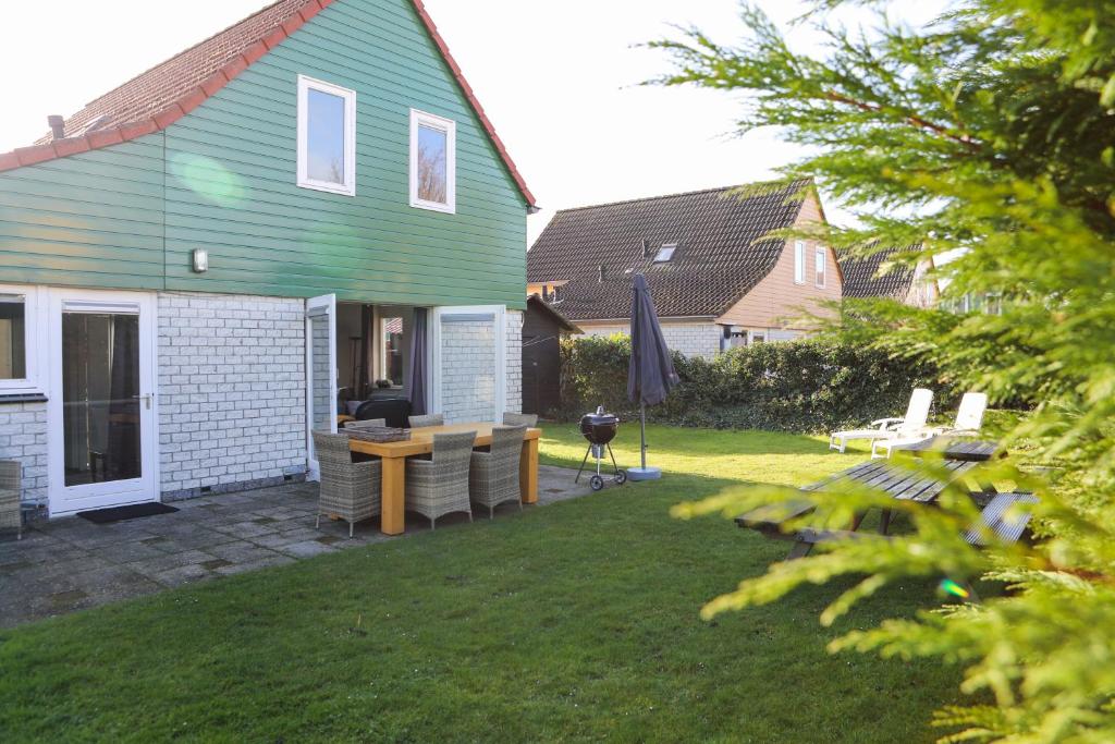 een huis met een tuin met een tafel en stoelen bij Vakantiewoning 114 in villapark de oesterbaai in Wemeldinge