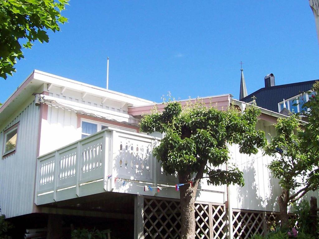 a white house with a balcony and a tree at 2 person holiday home in LYSEKIL in Lysekil