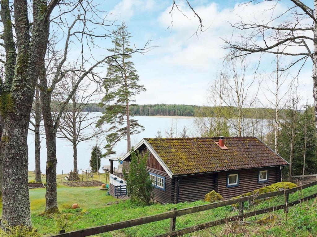uma cabana de madeira na margem de um lago em 4 person holiday home in VETLANDA em Lillarp