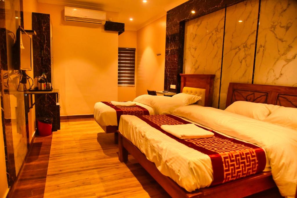 una camera d'albergo con tre letti e una televisione di SSK MALLIGAI RESIDENCY a Rāmanathapuram