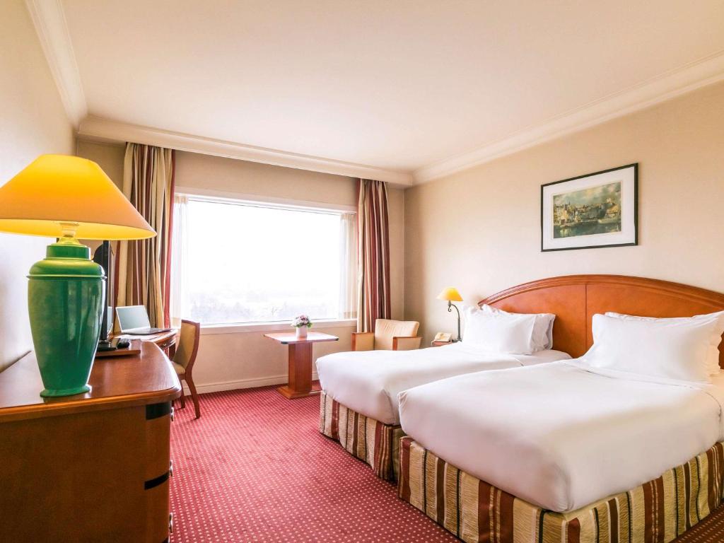 a hotel room with two beds and a window at Pullman Bucharest World Trade Center in Bucharest