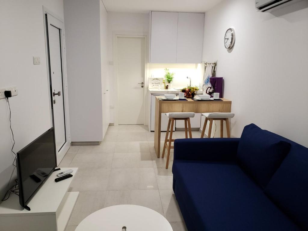a living room with a blue couch and a kitchen at Modern & Cozy Studio w/ Backyard Near City Center in Limassol