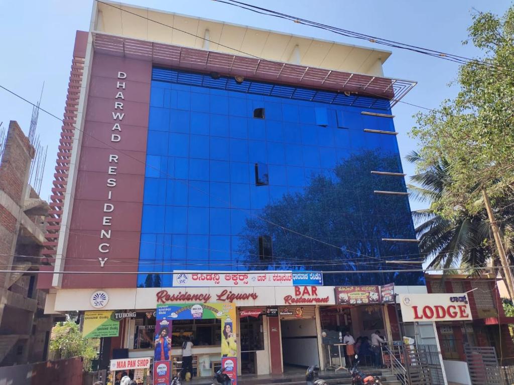 duży niebieski budynek po stronie ulicy w obiekcie Dharwad Residency w mieście Dharwad