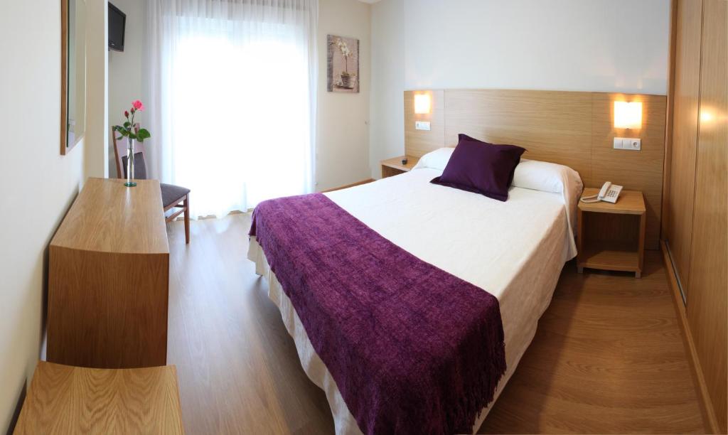 Habitación de hotel con cama grande con manta morada en Hotel Brisa del Mar, en O Grove