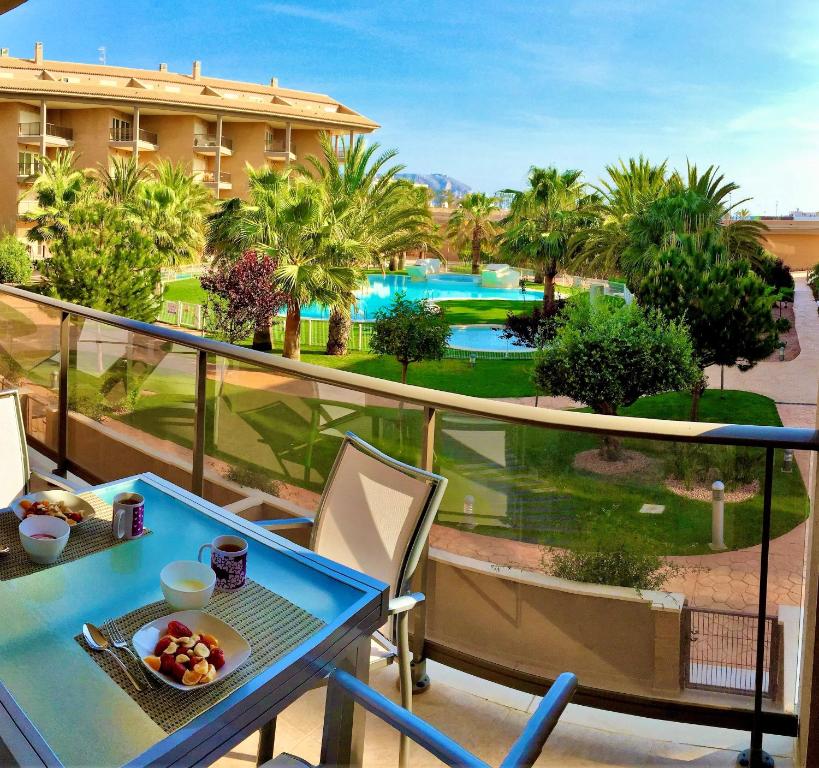een tafel en stoelen op een balkon met uitzicht op een resort bij Luxury Apartment 1st line Javea Arenal Beach in Jávea