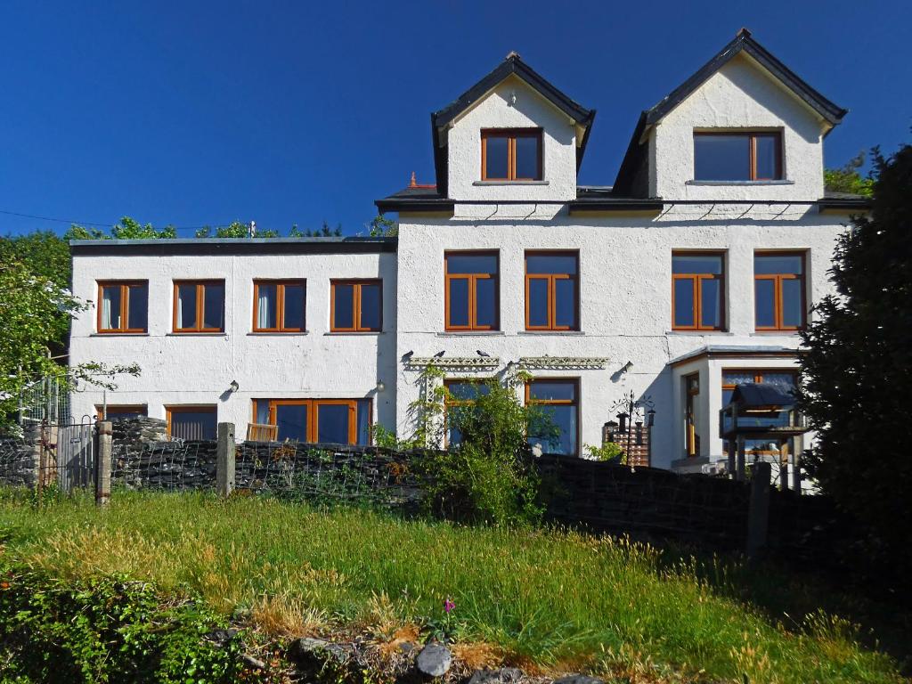 a white building with orange windows on a hill at Bryn Melyn Apartments in Barmouth