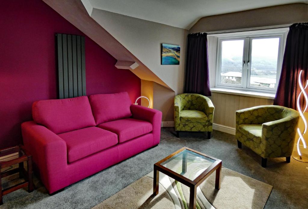 a living room with a purple couch and two chairs at Bryn Melyn Apartments in Barmouth