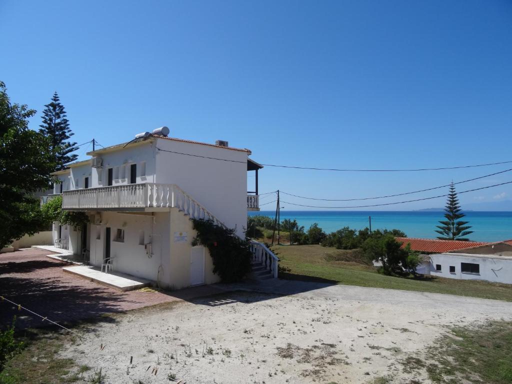 une maison blanche avec l'océan en arrière-plan dans l'établissement Anatoli Apartments, à Agios Stefanos