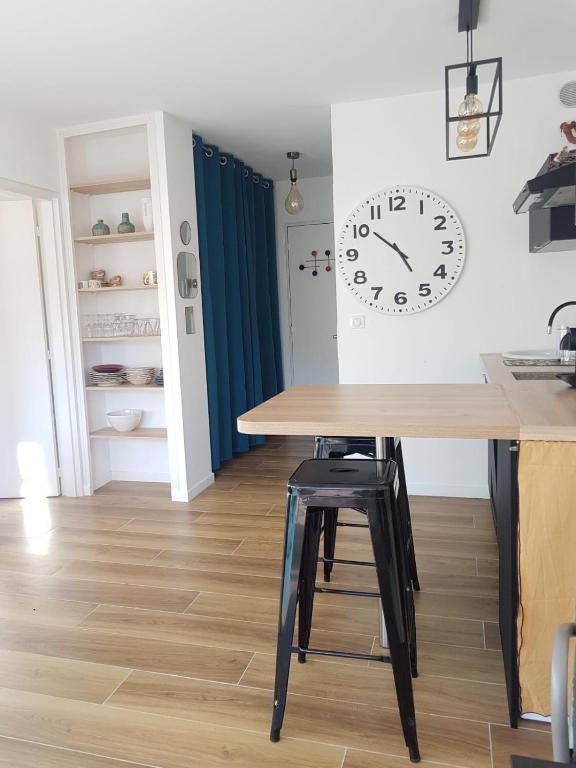 une salle à manger avec une table et une horloge au mur dans l'établissement Appartement deux pièces , climatisé, terrase, Cavalaire, à Cavalaire-sur-Mer